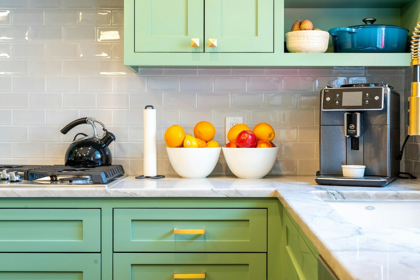 Sage green kitchen cabinetry with brass details